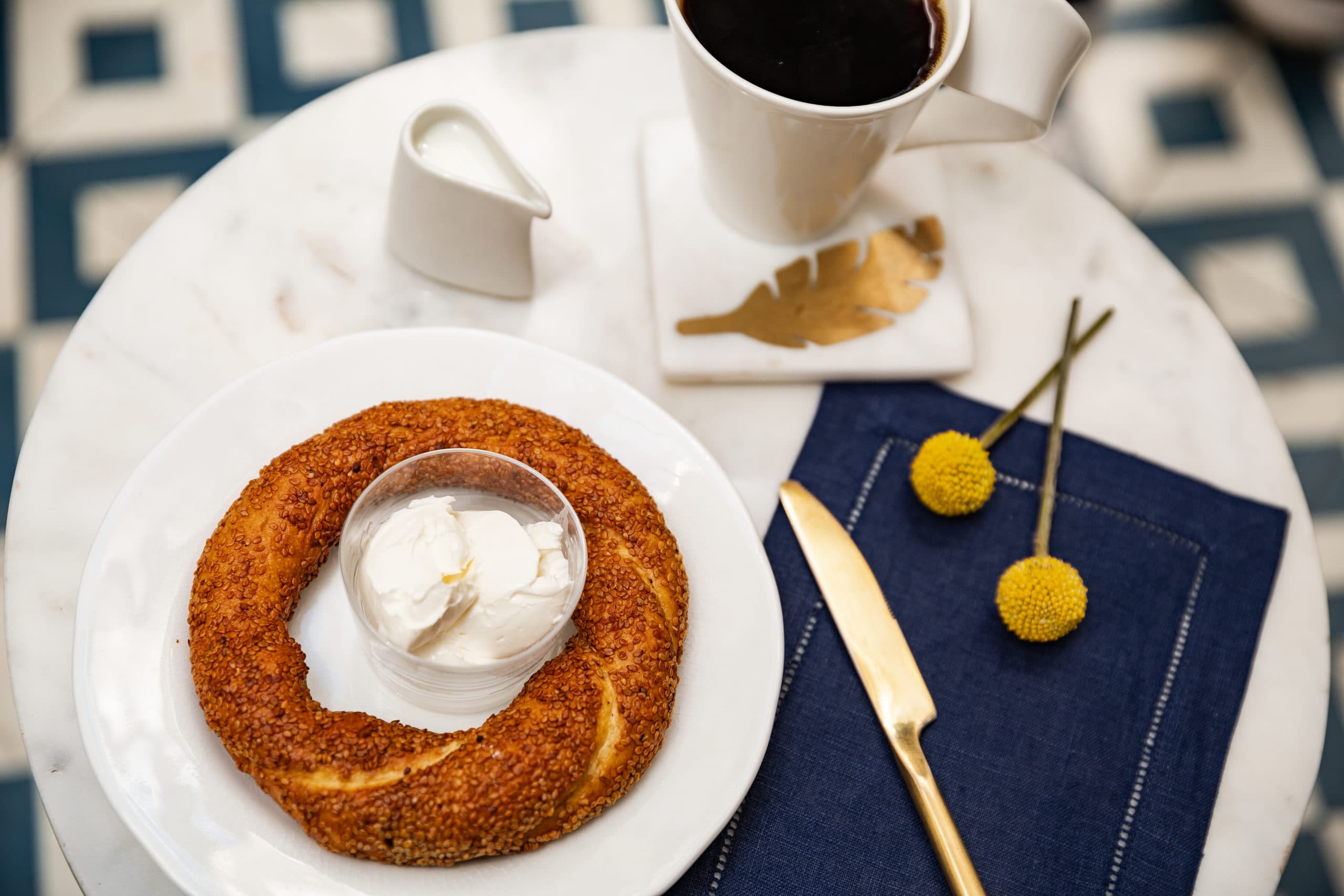 Simit with cream cheese and black coffee on white marble — Café Georgetown Georgetown DC